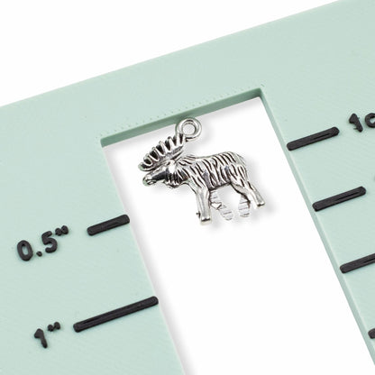 Hackberry Creek silver moose charm pendant with detailed walking design on a measuring tool for scale