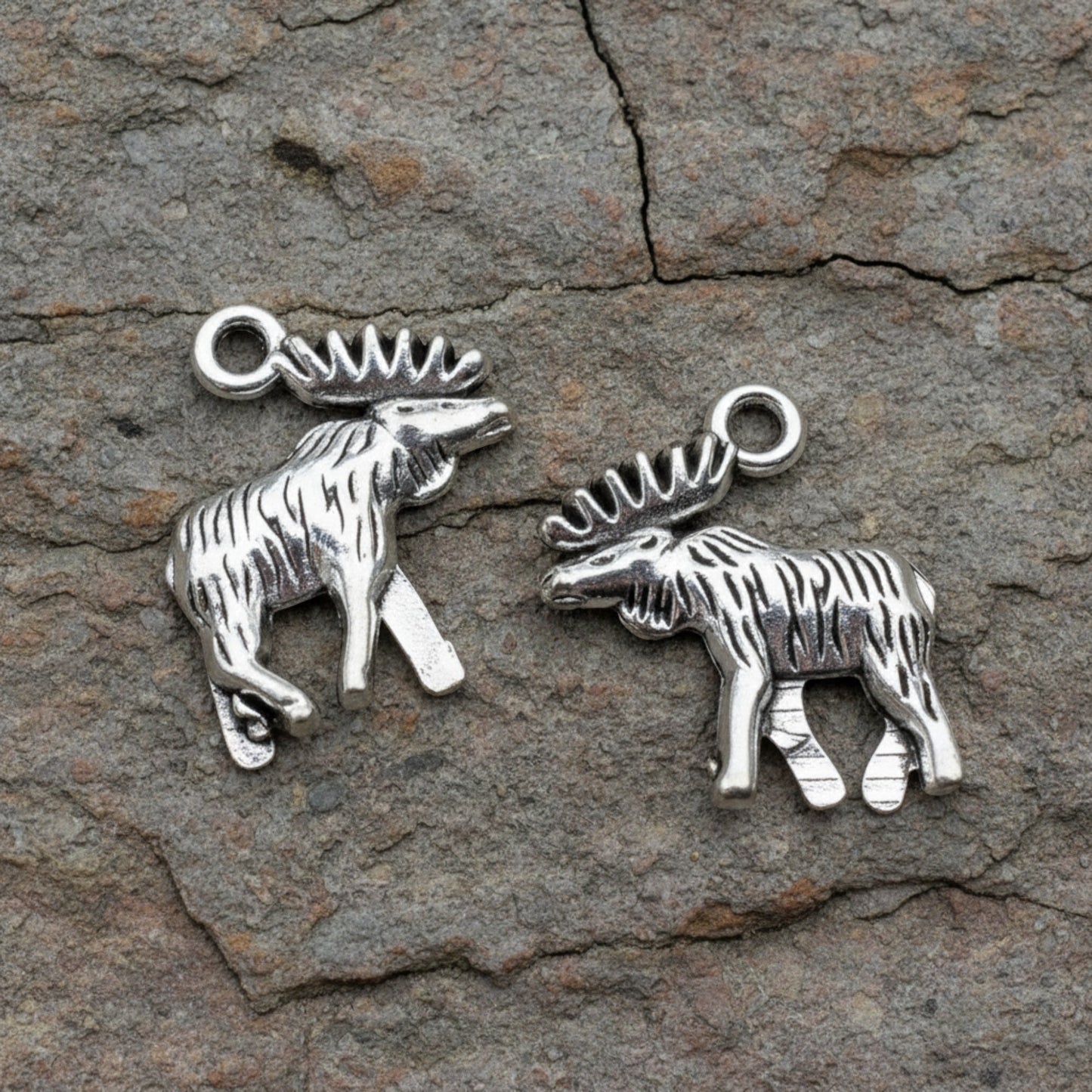 Hackberry Creek silver moose and elk metal charms with detailed walking posture on a rustic stone background