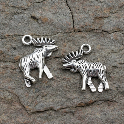Hackberry Creek silver moose and elk metal charms with detailed walking posture on a rustic stone background