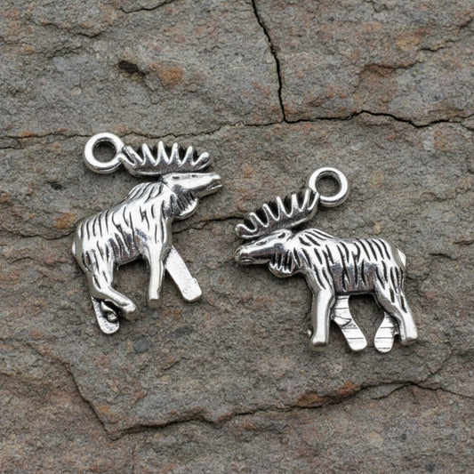 Hackberry Creek silver moose and elk metal charms with detailed walking posture on a rustic stone background