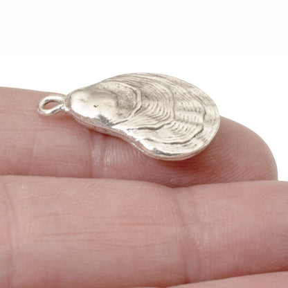Hackberry Creek silver oyster shell charm held on a finger, featuring detailed antique finish pewter construction.