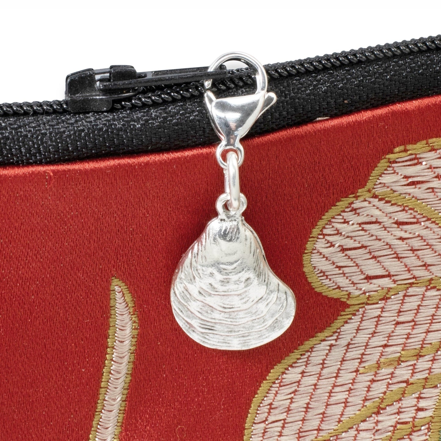 Hackberry Creek silver oyster shell charm with lobster clasp attached to a red embroidered fabric zipper pull
