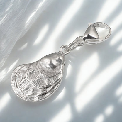 Hackberry Creek silver oyster shell charm with a lobster clasp, featuring detailed 3D texture for coastal jewelry.