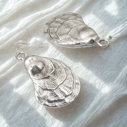 Hackberry Creek silver oyster shell charms with antique finish, perfect for coastal jewelry and ocean-inspired crafts.