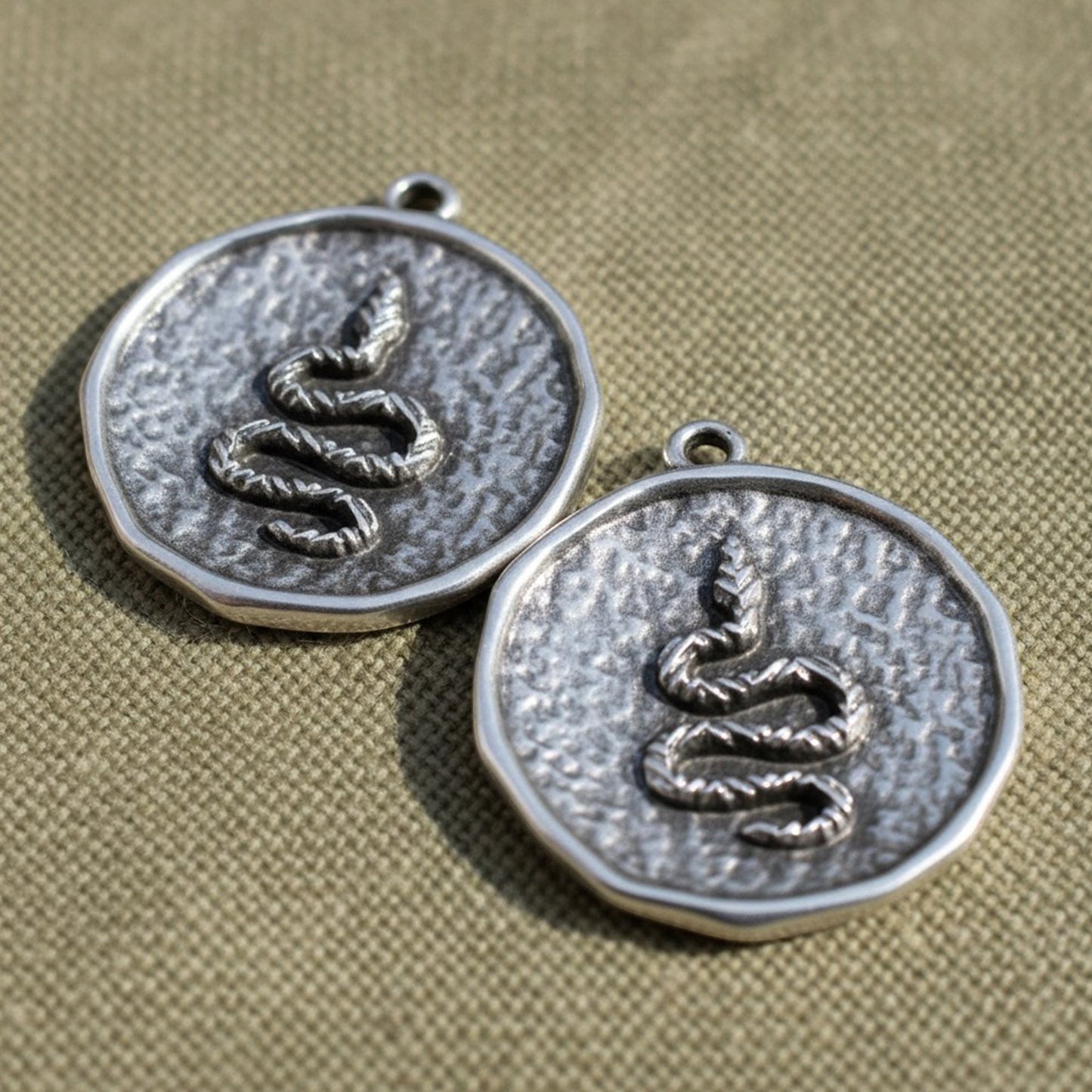 Hackberry Creek two silver-plated hammered coin pendants with a raised serpent relief design and antique finish.
