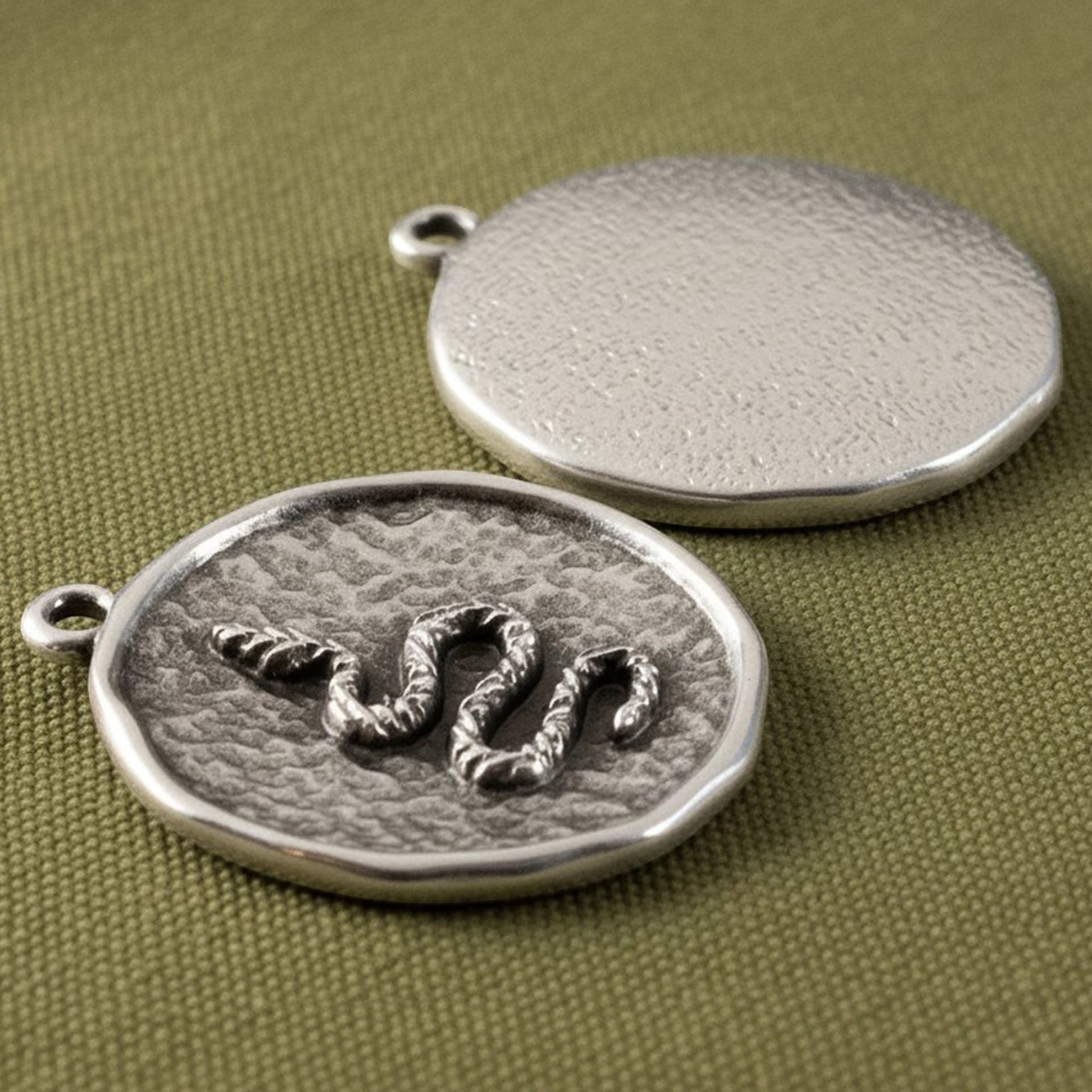Hackberry Creek two silver plated hammered coin pendants with raised serpent relief and antique finish.