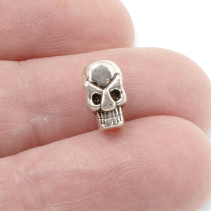 Hackberry Creek antique silver 3D skull alloy bead held between fingers for scale in jewelry making