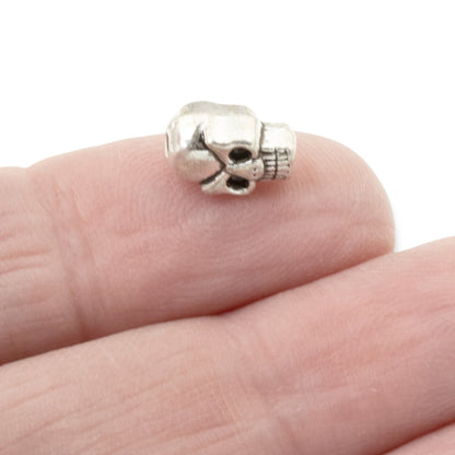 Hackberry Creek antique silver 3D skull alloy bead held on a finger for scale in jewelry making