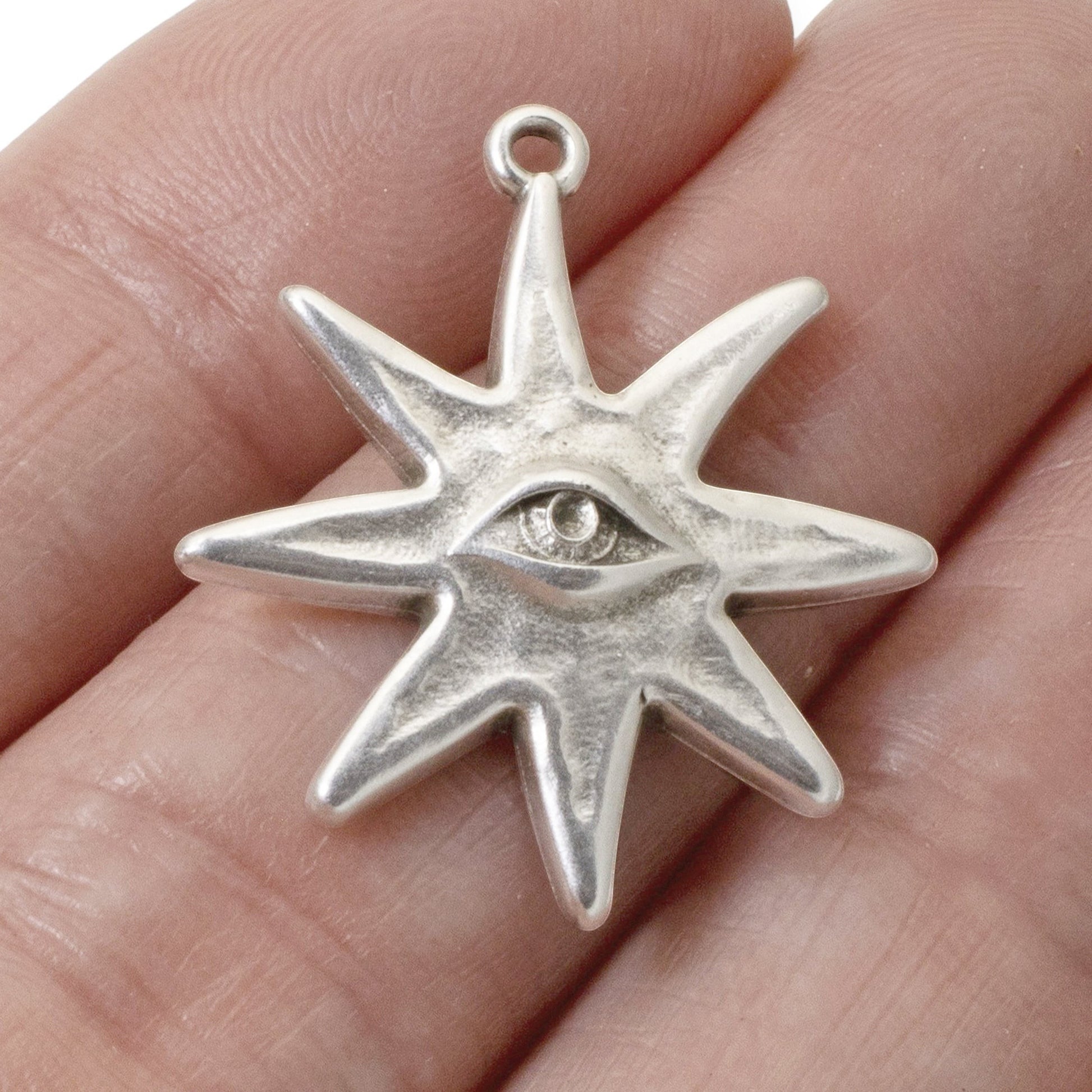 Hackberry Creek sterling silver-plated star eye pendant charm held in a hand for scale.