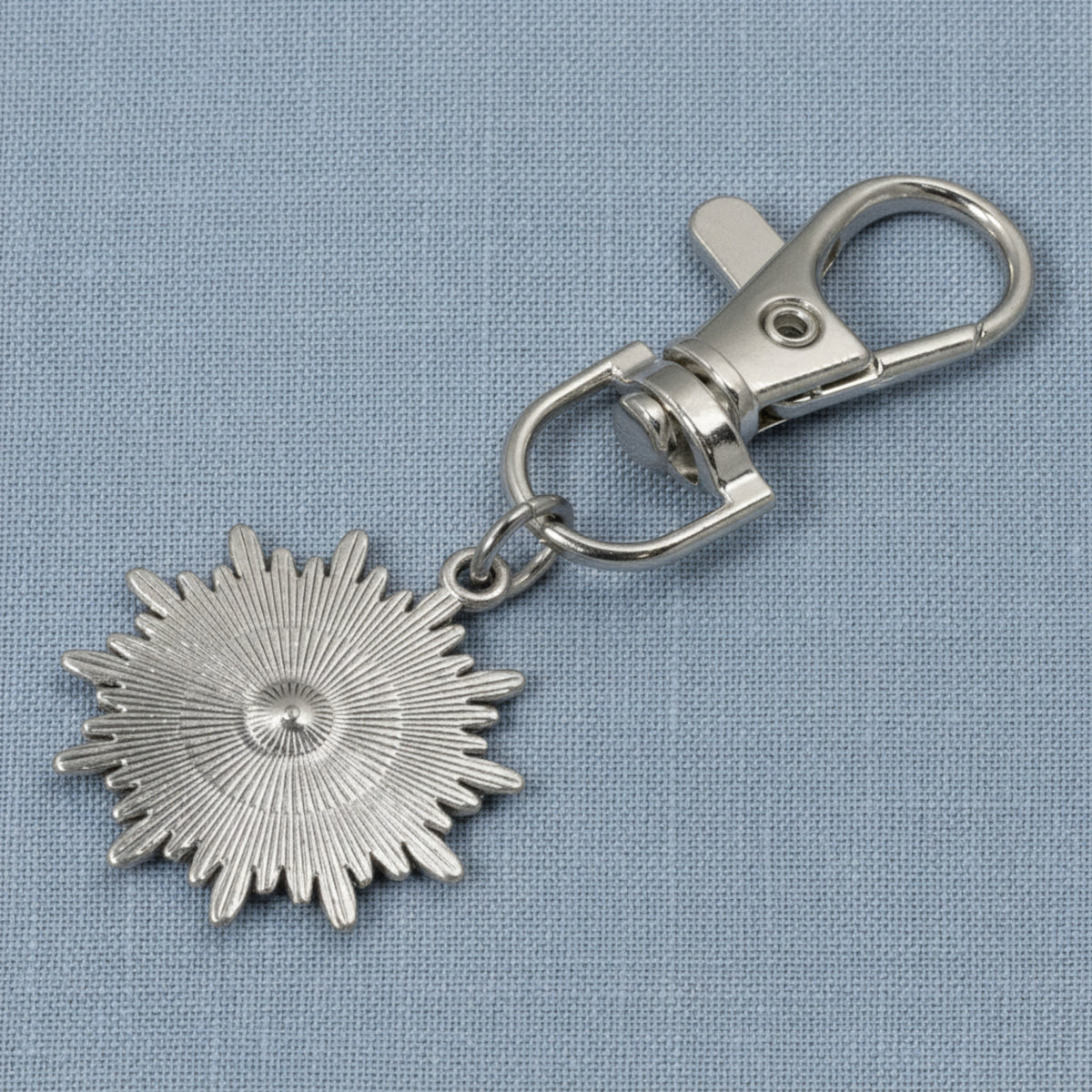 Hackberry Creek silver metal alloy sunburst evil eye key fob charm with a clear rhinestone accent on a blue background