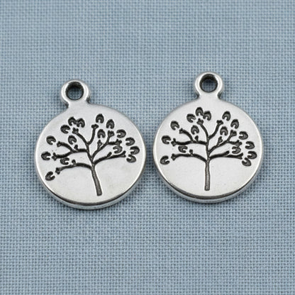 Hackberry Creek antique silver tree of life coin charms for spiritual jewelry making on a blue fabric background
