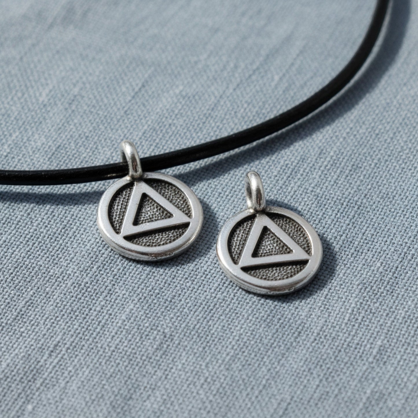 Hackberry Creek silver triangle recovery charms with antique oxidized finish on black leather cord.