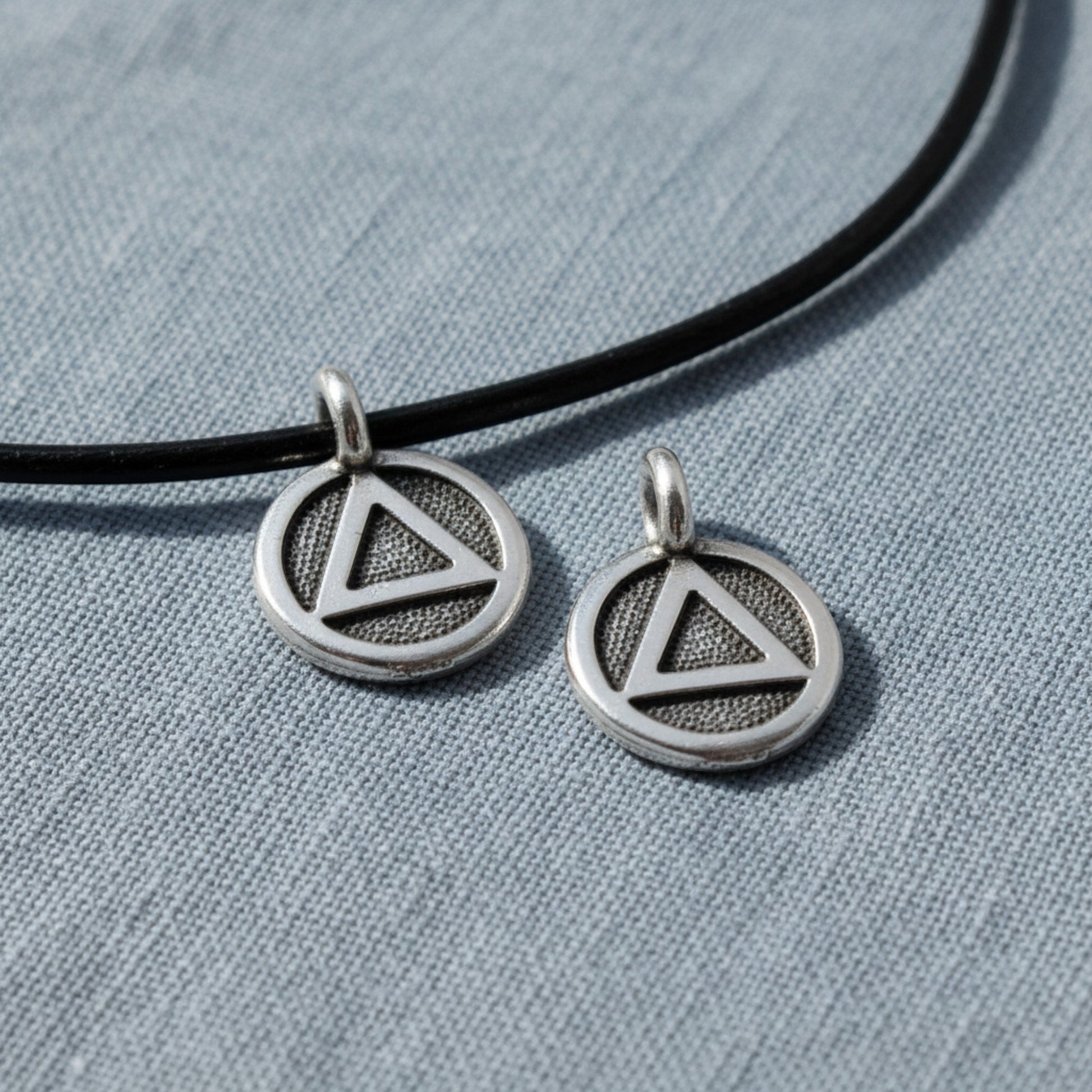 Hackberry Creek silver triangle recovery charms with antique oxidized finish on black leather cord.