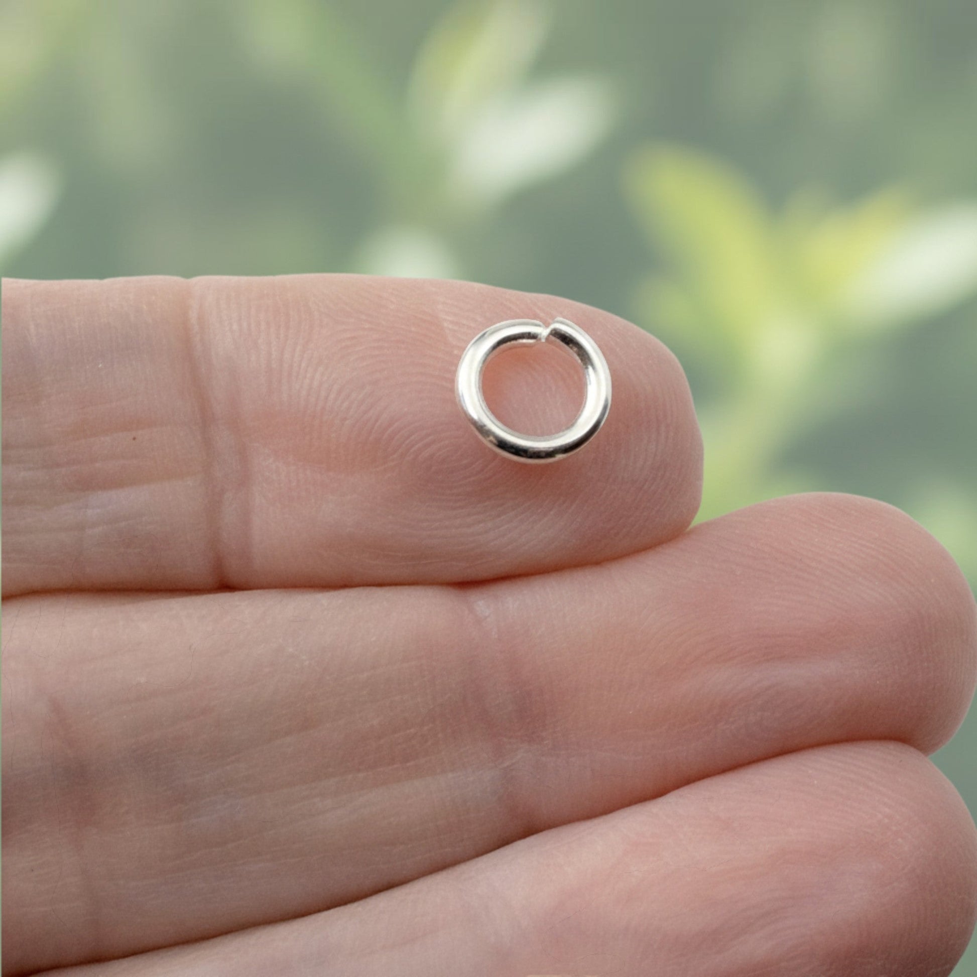 Hackberry Creek 8mm bright silver 304 stainless steel heavy duty jump ring held on a fingertip