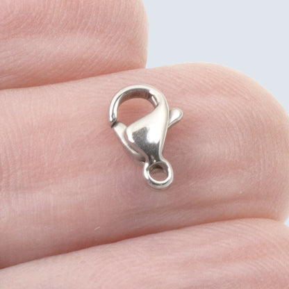 Hackberry Creek 6x9mm dark silver stainless steel lobster claw clasp held on a finger for scale