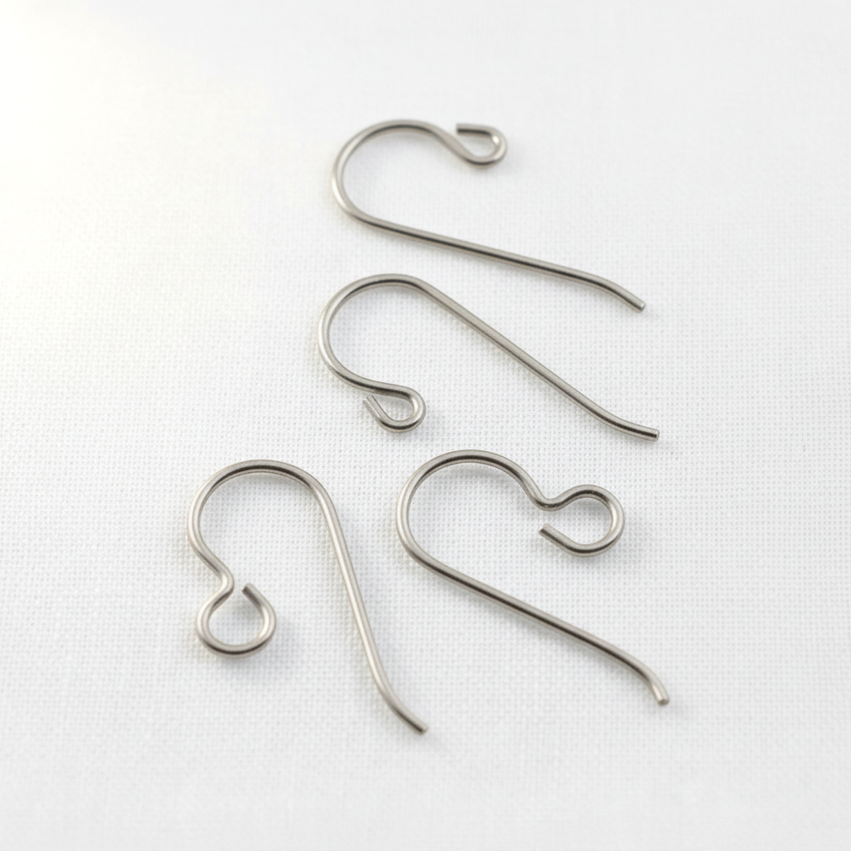 Hackberry Creek hypoallergenic titanium earring hooks in regular and front loop styles on a white fabric background.