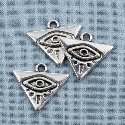 Hackberry Creek antique silver triangle evil eye charms for mystical jewelry making on a blue fabric background