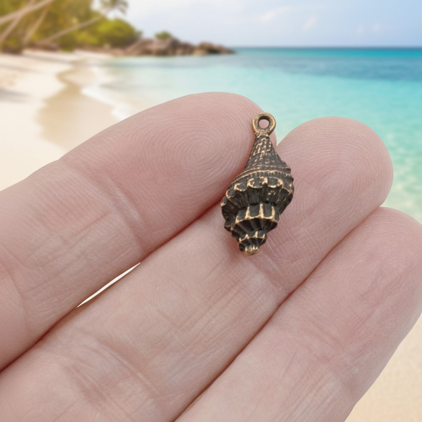 Hackberry Creek 21mm antique copper plated pewter trumpet shell charm with intricate spiral detail.